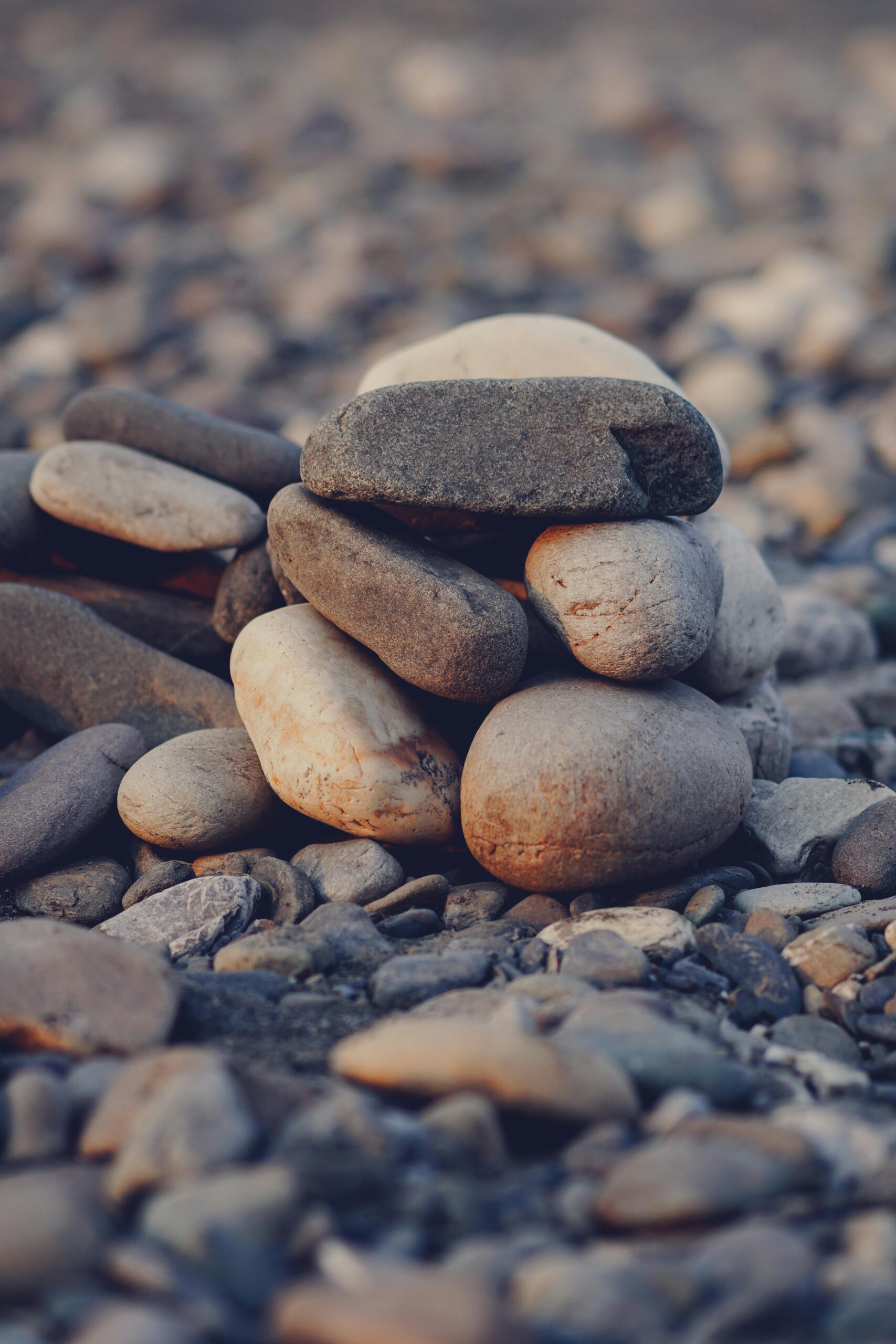A carefully balanced stack of smooth stones on a pebble beach, creating a calming natural pattern.